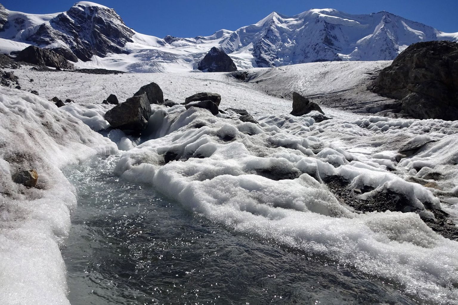 Meltwater streams on the Pers Glacier (GR). The summit regions are shining white as early as September due to fresh snow.