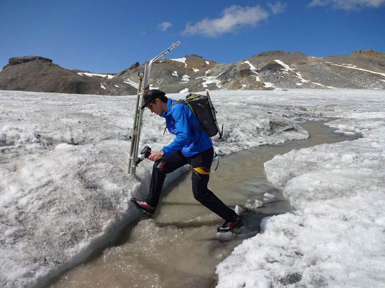 Mit Messmaterial über einen der vielen Schmelzwasserbäche auf dem Glacier de la Plaine Morte (BE).