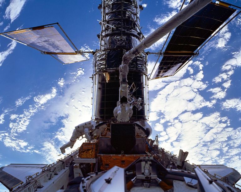 Die beiden Astronauten, C. Michael Foale, links und Claude Nicollier (auf dem Roboterarm der Discovery) während der Hubble Servicing Mission im Dezember 1999.
